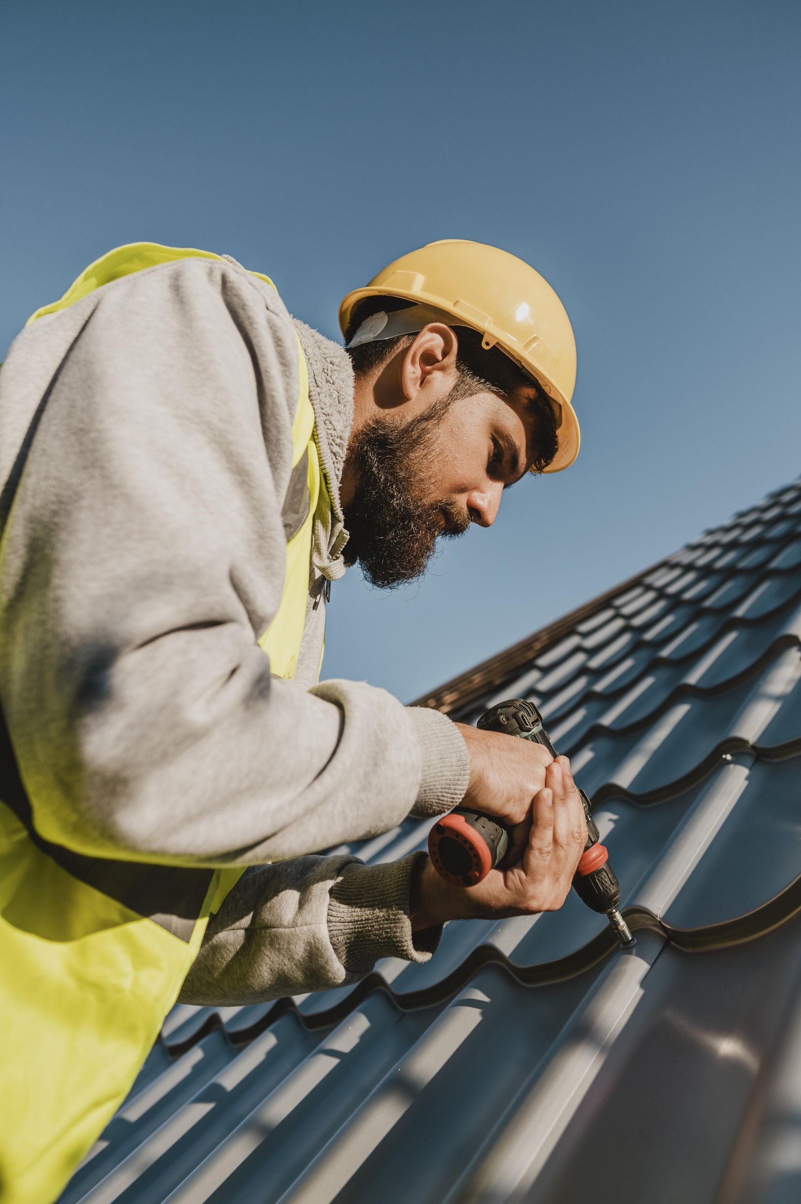 Roofer installing a metal roof under a clear California sky